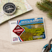 America the Beautiful National Park pass with a compass and map on a wooden surface